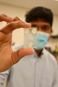 University of Cincinnati graduate student Isteaque Ahmed holds up a lab on chip in the remote diagnostics lab at UC. 
